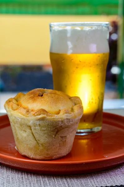 Traditional street food in England, glass of fresh lager beer and stuffed baked pie with pork meat