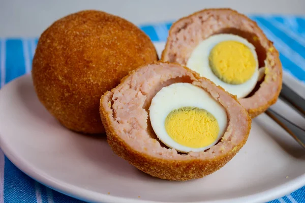 Traditional street food in UK, stuffed fried Scotch eggs with breadcrumbs close up
