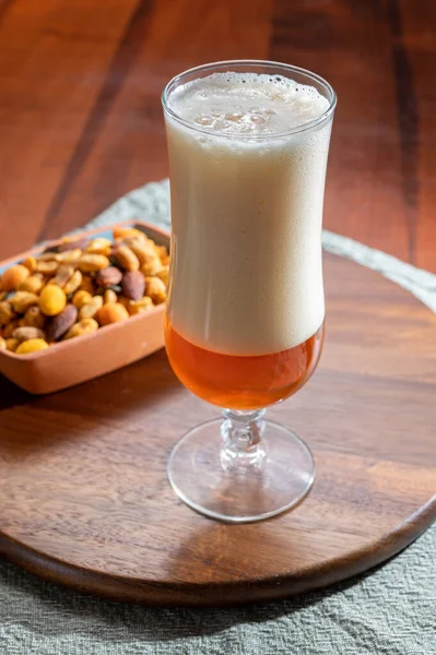 stock image Pouring of German wheat beer is glass and bowl with party mix nuts, close up