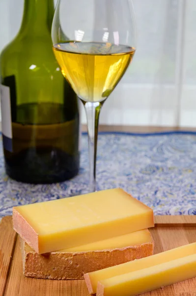 Wine and cheese pairing, local Comte cheese produced in the Franche-Comte region and glass and clavelin bottle special and characteristic yellow wine vin jaune from Jura region, France