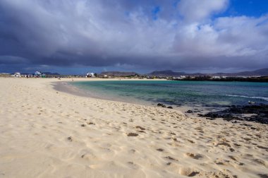 Beyaz kum, mavi su ve fırtınalı bulutlar La Concha sahilinde, El Cotillo sörfçülerinin köyü, Fuerteventura, Kanarya adaları, İspanya