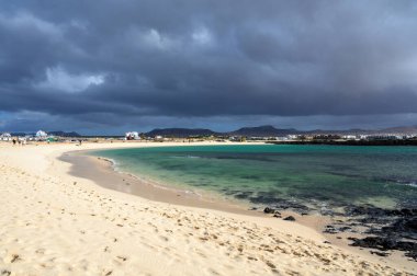 Beyaz kum, mavi su ve fırtınalı bulutlar La Concha sahilinde, El Cotillo sörfçülerinin köyü, Fuerteventura, Kanarya adaları, İspanya