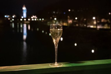 Tasting of french sparkling white wine with bubbles champagne outdoor at night with view on Marne river and lights of Epernay city in winter, France