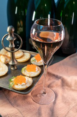 Tasting of brut Champagne sparkling wine with red caviar in cellars of gran cru wine house in Epernay, wine tour in Champagne, France, magnum bottles on background