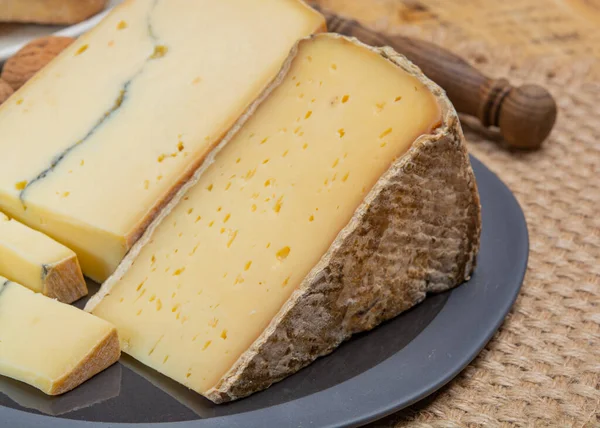 チーズコレクション フランスチーズモルビエセミソフト牛ミルクチーズ黒カビ層とトム サヴォワグレーの皮を閉じます — ストック写真