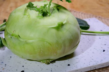 Fresh green kohlrabi with green leaves ready to eat from the garden, new harvest close up