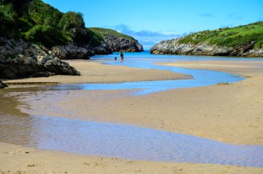 Playa de Poo 'ya bakın. Llanes yakınlarındaki gelgit sırasında, Asturias' ın yeşil kıyıları, Kuzey İspanya 'nın beyaz kumlu sahilleri, kayalıkları, gizli mağaraları, yeşil tarlaları ve dağları ile birlikte..