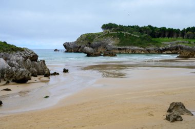 Celorio köyündeki Playa de Palombina Las Camaras 'ın manzarası, Kuzey İspanya, Asturias' ın yeşil kıyıları, kumlu plajları, kayalıkları, gizli mağaraları, yeşil tarlaları, ormanları ve dağları olan.