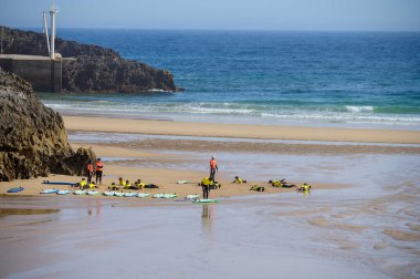 Genç sörfçüler, Celorio 'daki Playa de Palombina Las Camaras' ta, Kuzey İspanya, Asturias 'ın kumlu sahilleri, kayalıkları, gizli mağaraları, yeşil tarlaları ve dağları olan sörf tahtalimi yapıyorlar.