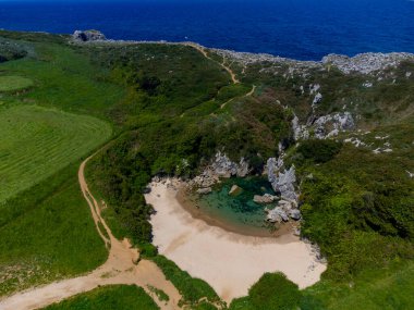 Küçük Playa de Gulpiyuri 'deki hava manzarası, dünyanın en kısa sahili olan Cantabrian Denizi' ne yaklaşık 100 metre mesafedeki Asturias Kuzey İspanya 'daki Llanes yakınlarındaki iç kıyılarla dolu subatan.