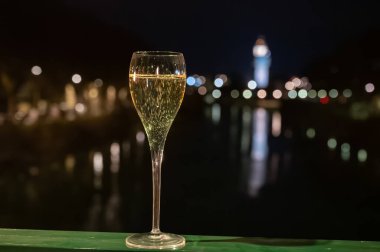 Tasting of french sparkling white wine with bubbles champagne outdoor at night with view on Marne river and lights of Epernay city in winter, France