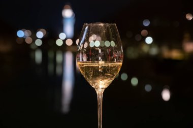 Tasting of french sparkling white wine with bubbles champagne outdoor at night with view on Marne river and lights of Epernay city in winter, France