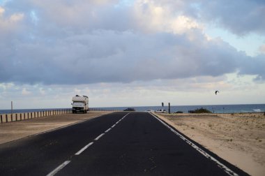 Corallejo sahilinin yakınlarındaki siyah kumlu kumsallarda Fuerteventura, Kanarya Adaları, İspanya 'daki renkli günbatımında araba sürüyorum.