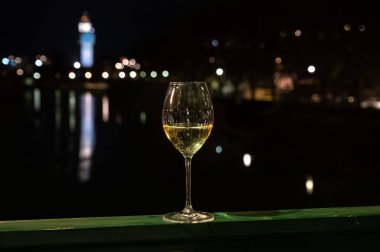 Tasting of french sparkling white wine with bubbles champagne outdoor at night with view on Marne river and lights of Epernay city in winter, France