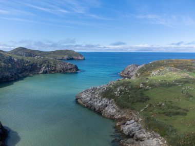 Playa de Poo 'daki hava manzarası, Llanes yakınlarındaki gelgit sırasında, Asturias, Kuzey İspanya' nın yeşil kıyıları, beyaz kumlu plajları, kayalıkları, gizli mağaraları, yeşil tarlaları ve dağları olan.