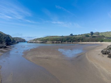 Playa de Poo 'daki hava manzarası, Llanes yakınlarındaki gelgit sırasında, Asturias, Kuzey İspanya' nın yeşil kıyıları, beyaz kumlu plajları, kayalıkları, gizli mağaraları, yeşil tarlaları ve dağları olan.