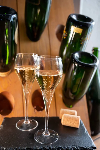 stock image Glasses of sparkling white wine champagne gran cru or cava with bubbles and classic wooden champagne pupitre rack with empty bottles on background
