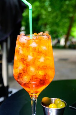 Garson Aperol Sprits yaz kokteylini Aperol, Prosecco, buz küpleri, tonik su ve portakalla hazırladı, güneşli terasta içmeye hazır.