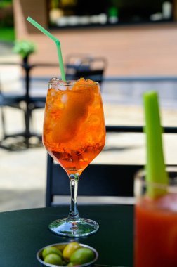 Garson Aperol Sprits yaz kokteylini Aperol, Prosecco, buz küpleri, tonik su ve portakalla hazırladı, güneşli terasta içmeye hazır.