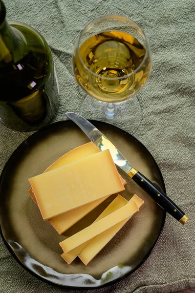 stock image Wine and cheese pairing, local Comte cheese produced in the Franche-Comte region and glass and clavelin bottle special and characteristic yellow wine vin jaune from Jura region, France