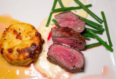 Kızarmış sığır eti ve patates ve krema soslu sebze ile servis edilen domuz eti.