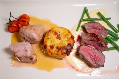 Kızarmış sığır eti ve patates ve krema soslu sebze ile servis edilen domuz eti.