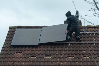 Bulutlu kış gününde evin çatısına güneş panelleri kurulması, Avrupa 'da yeşil enerji