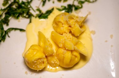 İtalyan yemeği, taze ev yapımı balkabağı dolması tortellini ya da parmesan parmesanlı İtalyan peyniri soslu ravioli hamuru ve beyaz tahtada kurutulmuş roket salatası.