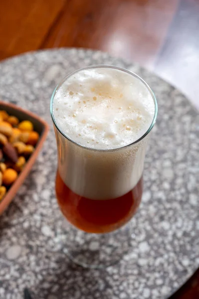 修道院で作られたベルギーのライトブロンドビールとパーティーミックスナッツとボウルのガラス クローズアップ — ストック写真