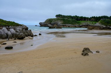 Celorio köyündeki Playa de Palombina Las Camaras 'ın manzarası, Kuzey İspanya, Asturias' ın yeşil kıyıları, kumlu plajları, kayalıkları, gizli mağaraları, yeşil tarlaları, ormanları ve dağları olan.