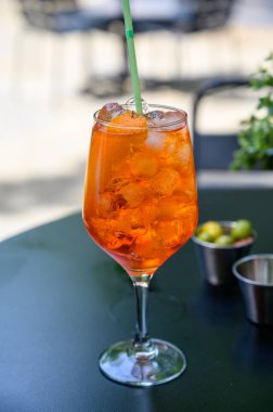 Garson Aperol Sprits yaz kokteylini Aperol, Prosecco, buz küpleri, tonik su ve portakalla hazırladı, güneşli terasta içmeye hazır.