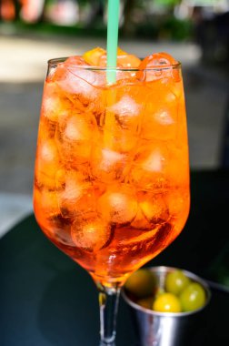 Garson Aperol Sprits yaz kokteylini Aperol, Prosecco, buz küpleri, tonik su ve portakalla hazırladı, güneşli terasta içmeye hazır.