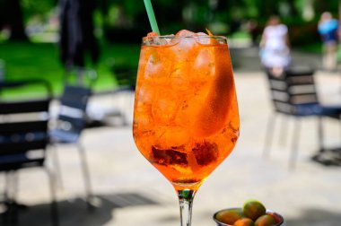 Garson Aperol Sprits yaz kokteylini Aperol, Prosecco, buz küpleri, tonik su ve portakalla hazırladı, güneşli terasta içmeye hazır.