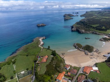 Playa de Palombina, Las Camaras ve Celorio 'daki hava manzarası, Asturias, Kuzey İspanya' nın yeşil kıyıları, beyaz kumlu plajları, kayalıkları, gizli mağaraları, yeşil tarlaları ve dağları olan.