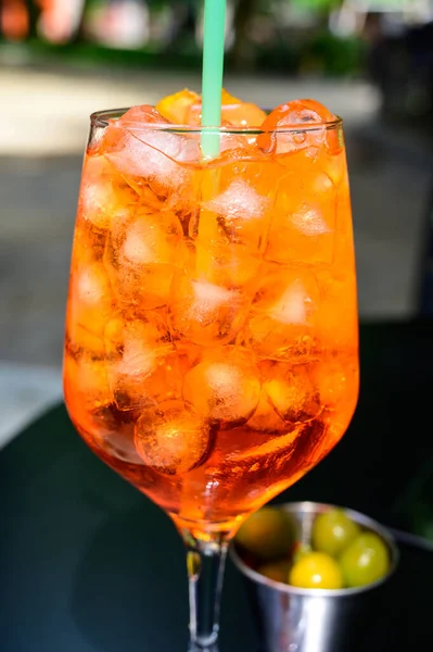 Garson Aperol Sprits yaz kokteylini Aperol, Prosecco, buz küpleri, tonik su ve portakalla hazırladı, güneşli terasta içmeye hazır.