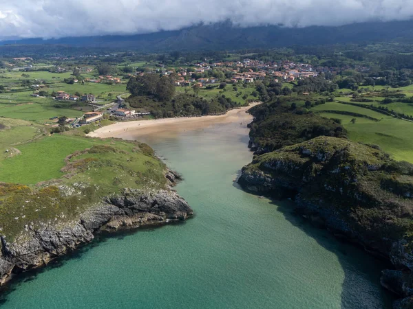 Playa de Poo 'daki hava manzarası, Llanes yakınlarındaki gelgit sırasında, Asturias, Kuzey İspanya' nın yeşil kıyıları, beyaz kumlu plajları, kayalıkları, gizli mağaraları, yeşil tarlaları ve dağları olan.