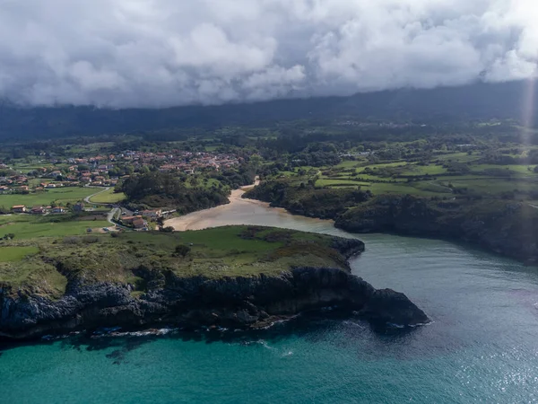 Playa de Poo 'daki hava manzarası, Llanes yakınlarındaki gelgit sırasında, Asturias, Kuzey İspanya' nın yeşil kıyıları, beyaz kumlu plajları, kayalıkları, gizli mağaraları, yeşil tarlaları ve dağları olan.