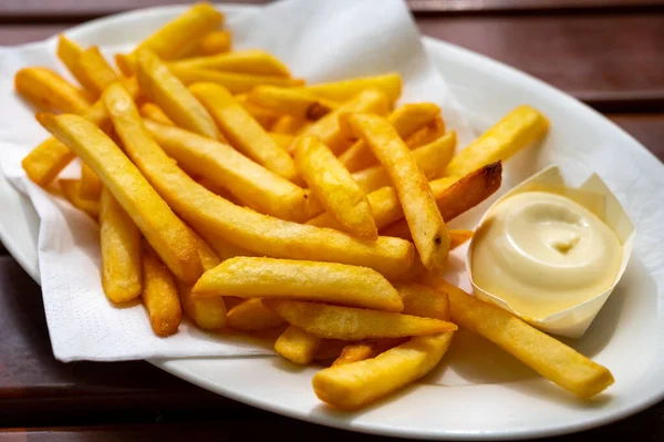 Eating of street or take away food fresh baked french fried potatoes chips with Belgian mayonnaise, close up