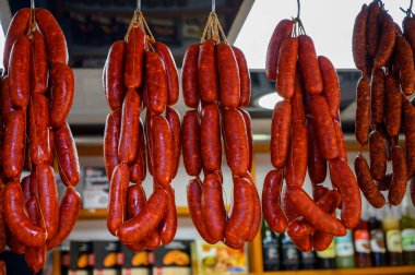 Spanish pork sausages chorizo hanging on butchers shop on farmers market clipart