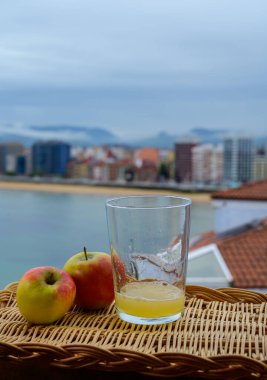 Tahta fıçıdaki mayalanmış elmalardan yapılan geleneksel Asturian şarabı hava kabarcıkları için büyük bir yükseklikten San Lorenzo sahilindeki içecek ve manzaraya dökülmelidir.