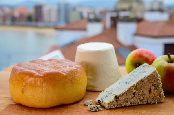 stock image Asturian cheeses, hard smoked cow cheese from Pria, blue cheese cabralis from Arenas and white rebollin from Pitu, Asturias, served outdoor with view on San Lorenzo beach in Gijon, Spain