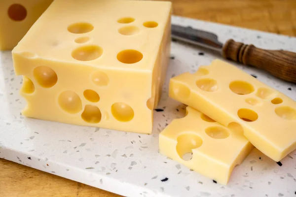 チーズコレクション 穴の開いたフランスのハードチーズのブロックメンターラーを閉じます — ストック写真