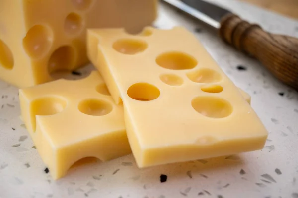 Cheese collection, block of french hard cheese with holes emmentaler close up