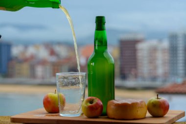 Tahta fıçıdaki mayalanmış elmalardan yapılan geleneksel Asturian şarabı hava kabarcıkları için büyük bir yükseklikten San Lorenzo sahilindeki içecek ve manzaraya dökülmelidir.