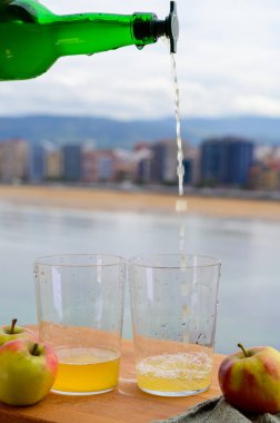 Tahta fıçıdaki mayalanmış elmalardan elde edilen doğal Asturian şarabı, hava kabarcıkları için büyük bir yükseklikten San Lorenzo sahilindeki içme ve manzaraya dökülmelidir.