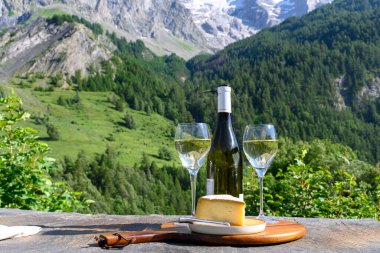 Peynir ve şarap, Savoy bölgesinden beyaz Roussette de Savoie ve Vin de Savoie şarabı ve yazın üstleri karlı Hautes Alpes dağları manzaralı..