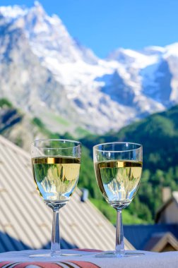 Savoy bölgesinden gelen beyaz Roussette de Savoie ve Vin de Savoie Fransız şarabı içerken yaz aylarında Hautes Alpes dağlarının zirvesinde kar manzaralı.