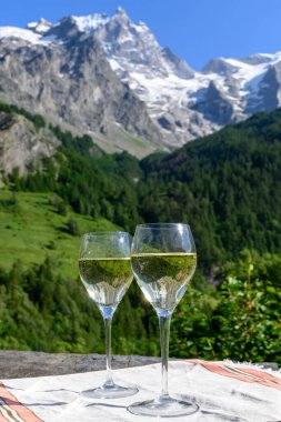 Savoy bölgesinden gelen beyaz Roussette de Savoie ve Vin de Savoie Fransız şarabı içerken yaz aylarında Hautes Alpes dağlarının zirvesinde kar manzaralı.