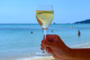 Provence 'de yaz zamanı, Pampelonne' da bir bardak soğuk beyaz şarap güneşli bir günde Saint-Tropez yakınlarındaki kumlu plajda, Var Bölümü, Fransa.