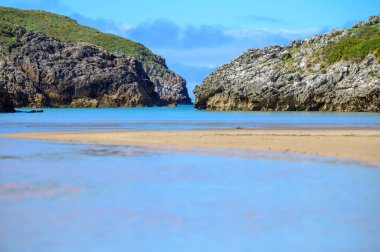 Playa de Poo 'ya bakın. Llanes yakınlarındaki gelgit sırasında, Asturias' ın yeşil kıyıları, Kuzey İspanya 'nın beyaz kumlu sahilleri, kayalıkları, gizli mağaraları, yeşil tarlaları ve dağları ile birlikte..